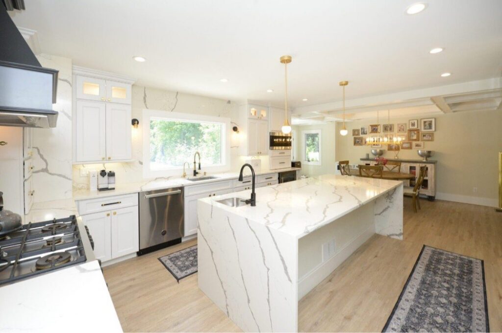 27-2048x1361 Spacious modern kitchen with white cabinets, marble countertops, and stainless steel appliances.
