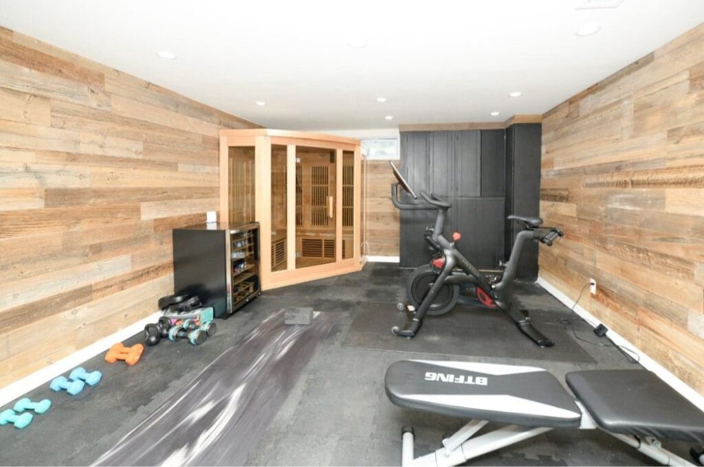 37-2048x1361 Home gym with exercise bike, sauna, weights, and wooden walls.