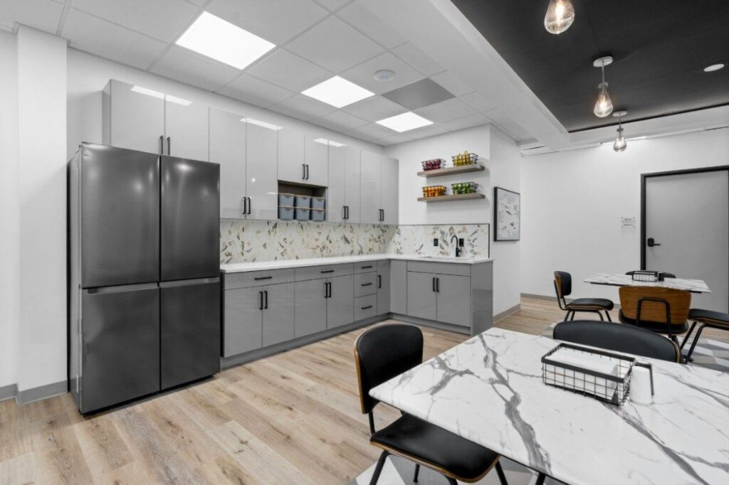Ikon-10-2048x1365 Modern kitchen and dining area with gray cabinets, marble countertops, and black fridge.